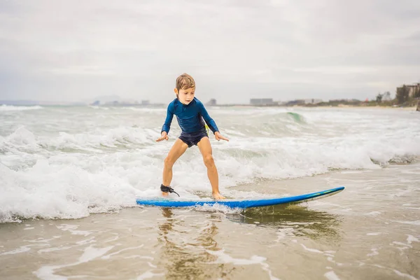 Jeune garçon en bonne santé apprenant à surfer dans la mer ou l'océan — Photo