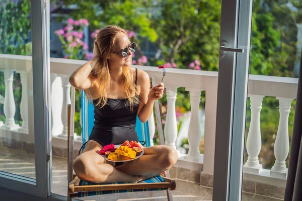 Jonge vrouw rustend op een balkon met een bord fruit. leven-werk balans, ontspanning gezonde kwaliteit leven levensstijl in de zomer vakantie van freelancer vrouw rustig rusten in resort — Stockfoto