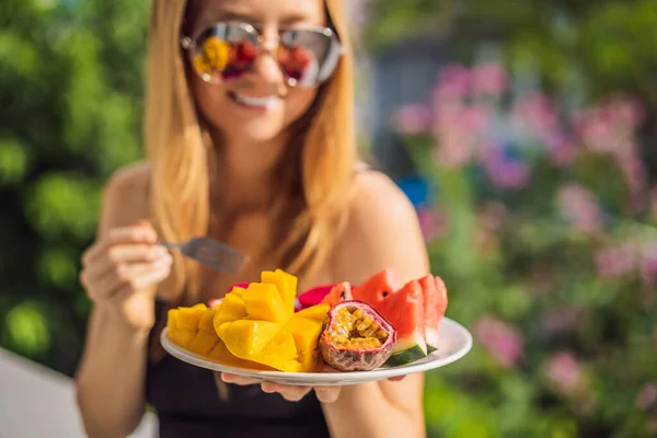 Ung kvinna vilar på en balkong med en tallrik frukt. liv-arbete balans, avkoppling hälsosam kvalitet livsstil på sommaren semester frilansare kvinna ta det lugnt vilar i resort — Stockfoto