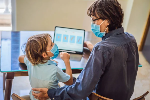 Anak itu belajar online di rumah menggunakan tablet. Ayah membantunya belajar. Ayah dan anak dalam masker medis untuk melindungi terhadap coronovirus. Belajar selama karantina. pandemi global covid19 virus — Stok Foto