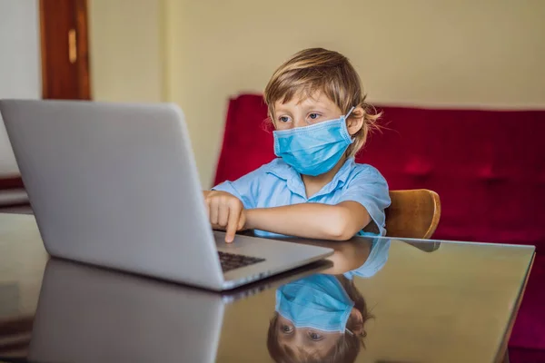 Chłopiec studiuje online w domu za pomocą laptopa w maskach medycznych w celu ochrony przed koronowirusem. Uczę się podczas kwarantanny. Globalny wirus pandemii19 — Zdjęcie stockowe