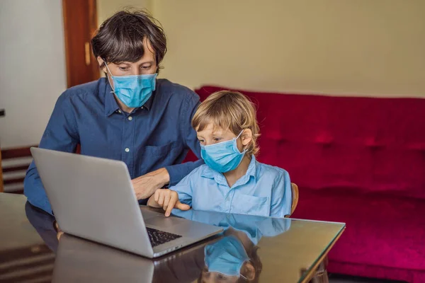 Chłopak uczy się online w domu za pomocą laptopa. Ojciec pomaga mu się uczyć. Ojciec i syn w maskach medycznych do ochrony przed koronowirusem. Uczę się podczas kwarantanny. Globalny wirus pandemii19 — Zdjęcie stockowe