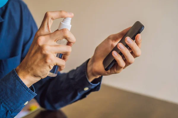 アルコールや消毒剤でスマートフォンの画面を掃除男。細菌による病気の予防のための汚れたスクリーン電話のクリーニングの概念。コロナウイルスcovid 19 — ストック写真
