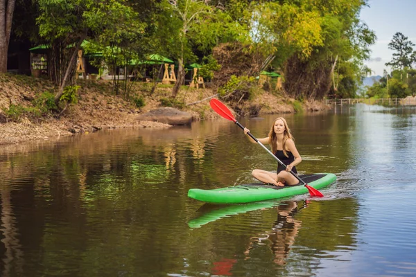 SUP Stand up paddle board mujer paddle boarding on lake standing happy on paddleboard on blue water. Tiro de acción de mujer joven en el tablero de la paleta — Foto de Stock