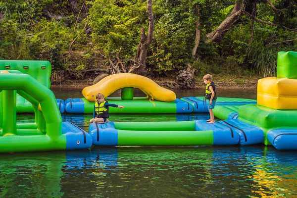 Zwei Jungen laufen einen aufblasbaren Hindernisparcour im See — Stockfoto