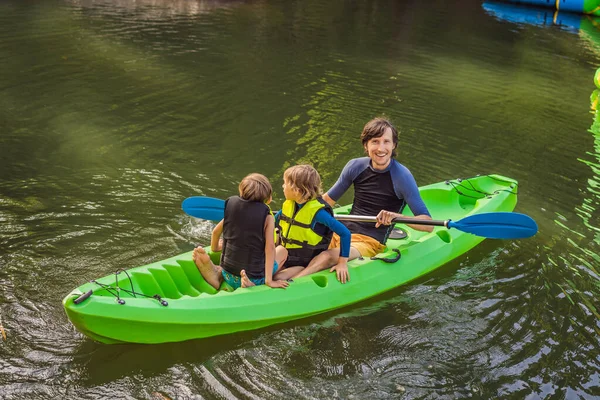 Egy férfi és két fiú egy kajakban a folyón. Boldog gyermekkort! — Stock Fotó