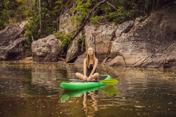 SUP Stand Up Paddle Board Frau paddelt auf dem See stehend glücklich auf dem Tretbrett auf blauem Wasser. Action Shot von junger Frau auf Paddelbrett — Stockfoto