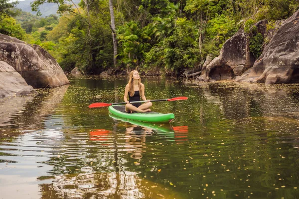 SUP Levante-se paddle board mulher paddle embarque no lago de pé feliz em paddleboard em água azul. Ação tiro de jovem mulher no tabuleiro de remo — Fotografia de Stock