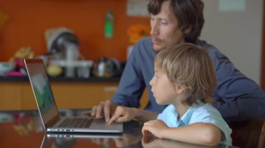 Genç bir adam ve küçük oğlu karantina sırasında bir evde oturup internet okulunda tablet kullanarak okuyorlar. Corona virüsü konsepti