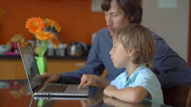 Genç bir adam ve küçük oğlu karantina sırasında bir evde oturup internet okulunda tablet kullanarak okuyorlar. Corona virüsü konsepti