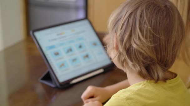 Een jonge vrouw en haar zoontje zitten tijdens de quarantaine in een tehuis en studeren op de internetschool met een tablet. Corona-virusconcept — Stockvideo