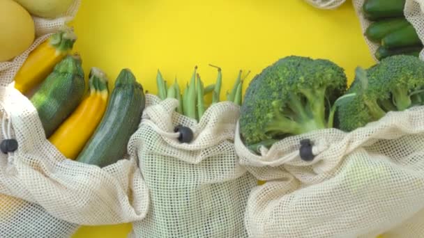 Frutas y verduras coloridas en bolsas reutilizables sobre un fondo amarillo. Cero residuos. Reducir el concepto de residuos plásticos — Vídeo de stock