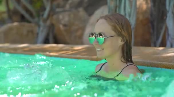 热带度假胜地的一位年轻女子，温泉、瀑布和游泳池都有热水 — 图库视频影像