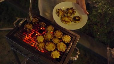 Gece barbekü. Adam ızgarada sebze pişiriyor.