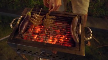 Gece barbekü. Adam ızgarada sebze pişiriyor.