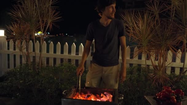 Um churrasco à noite. Homem cozinha legumes em uma grelha — Vídeo de Stock