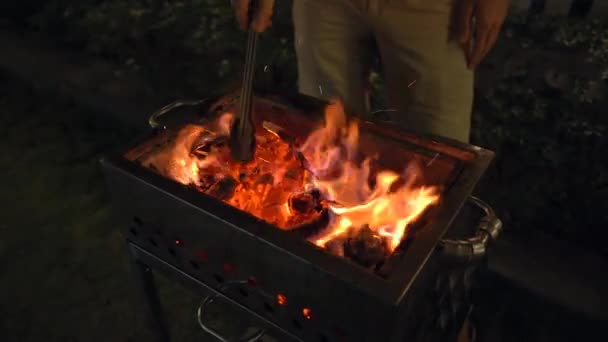 A barbeque at night. Man cooks vegetables on a grill — Stock Video