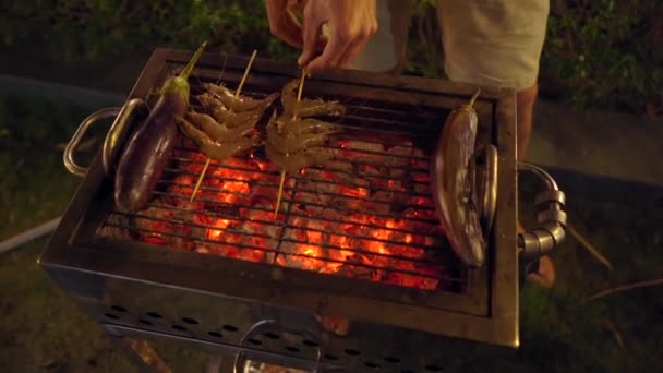 Grillfest om kvelden. Mennesket lager grønnsaker på grillen – stockvideo