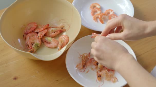 Une femme épluche des crevettes sur une table en bois — Video