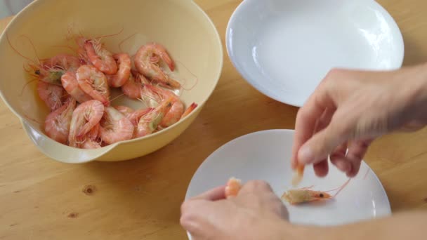 Un homme épluche des crevettes sur une table en bois — Video