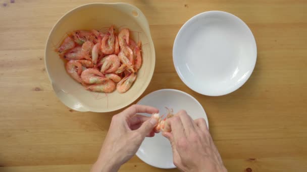 A man peels shrimps on a wooden table — Stock Video