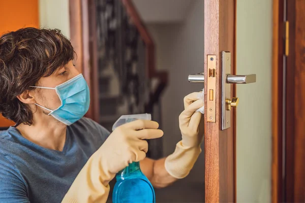 Coronovirus Prevention A man disinfects a doorknob. Closeup of a caucasian man disinfecting the door handle by spraying sanitizer from a bottle — Stock Photo, Image