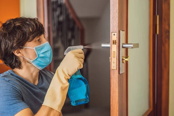 Coronovirus Prevention A man disinfects a doorknob. Closeup of a caucasian man disinfecting the door handle by spraying sanitizer from a bottle