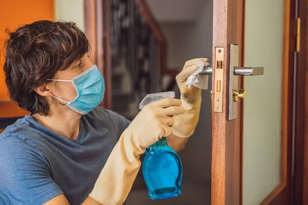 Coronovirus Prevention A man disinfects a doorknob. Closeup of a caucasian man disinfecting the door handle by spraying sanitizer from a bottle — Stock Photo, Image
