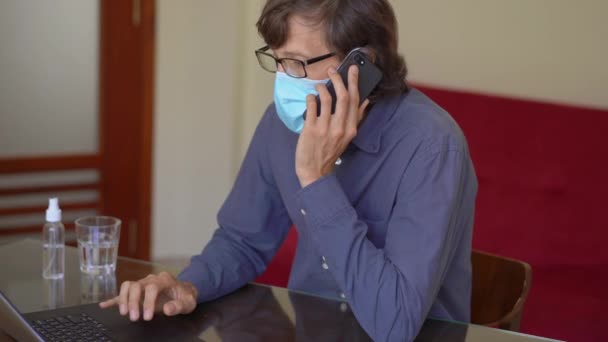 A young man wearing a face mask works from home during corona virus self isolation — Stock Video