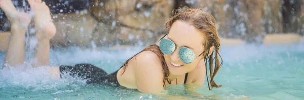 Jonge vrolijke vrouw onder de waterstroom, zwembad, spa overdag, warmwaterbronnen BANNER, LANG FORMAT — Stockfoto