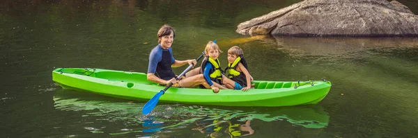 Een man en twee jongens in een kajak op de rivier. Gelukkige kindertijd BANNER, LANG FORMAT — Stockfoto