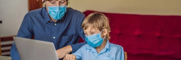 Boy studying online at home using laptop. Father helps him learn. Father and son in medical masks to protect against coronovirus. Studying during quarantine. Global pandemic covid19 virus BANNER, LONG