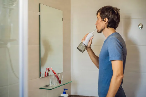 A man uses an oral irrigator in his bathroom — Stock Photo, Image