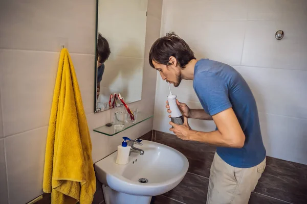 Un uomo usa un irrigatore orale nel suo bagno — Foto Stock