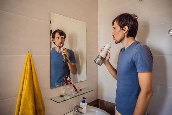 A man uses an oral irrigator in his bathroom — Stock Photo, Image