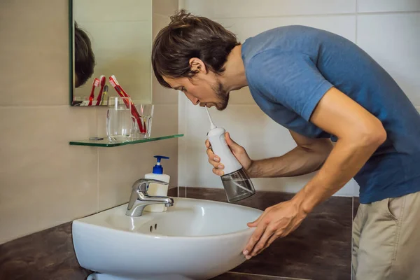 Um homem usa um irrigador oral em seu banheiro — Fotografia de Stock