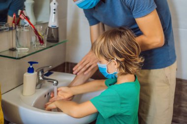 Baba oğluna ellerini doğru dürüst yıkamayı öğretiyor. Koronovirüs yüzünden maskeli baba ve oğul. Salgın hastalık. Evde kal. Ellerini yıka.