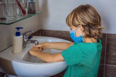 Çocuk ellerini sabunla yıkıyor. Koronavirüs yüzünden maske takan bir çocuk. Salgın. Evde kal. Ellerini yıka.