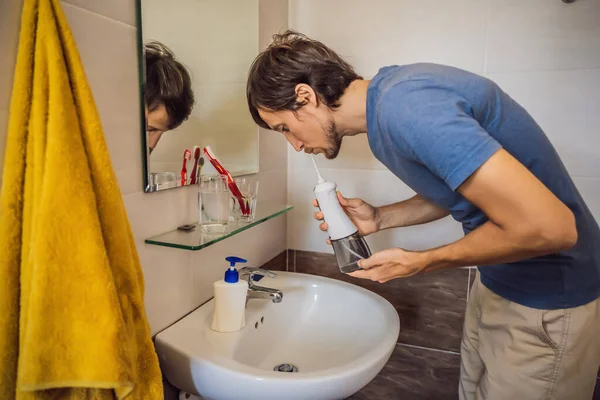Ein Mann benutzt ein orales Bewässerungsgerät in seinem Badezimmer — Stockfoto