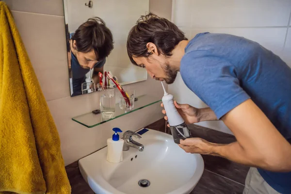 एक माणूस त्याच्या बाथरूममध्ये तोंडी सिंचन वापरतो — स्टॉक फोटो, इमेज