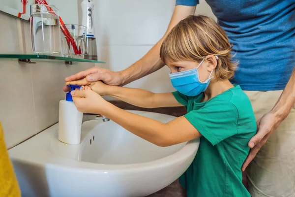 Dad teaches his son to wash his hands properly. Dad and son in medical masks because of coronovirus. Epidemic. Stay home. Wash your hands