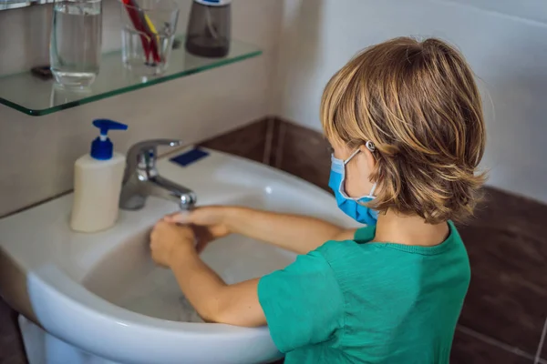 Boy washes his hands with soap. Boy in a medical mask due to coronavirus. Pandemic. Stay home. Wash your hands — Stock Photo, Image