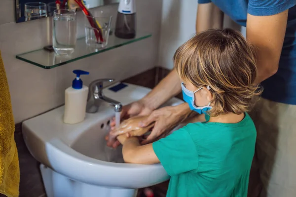 Tata uczy syna, jak prawidłowo myć ręce. Tata i syn w maskach medycznych z powodu koronowirusa. Epidemia. Zostań w domu. Umyj ręce. — Zdjęcie stockowe