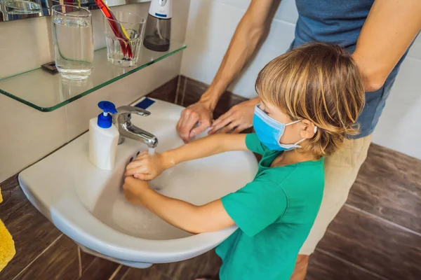 Tata uczy syna, jak prawidłowo myć ręce. Tata i syn w maskach medycznych z powodu koronowirusa. Epidemia. Zostań w domu. Umyj ręce. — Zdjęcie stockowe