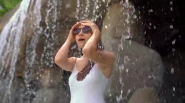 Sıcak pınarları, şelaleleri ve sıcak maden suyu olan yüzme havuzları olan tropikal bir tatil köyünde genç bir kadın. Yavaş çekim.