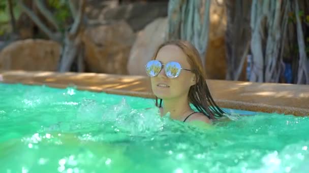 Eine junge Frau in einem tropischen Resort mit heißen Quellen, Wasserfällen und Schwimmbädern mit heißem Mineralwasser. Zeitlupenschuss — Stockvideo