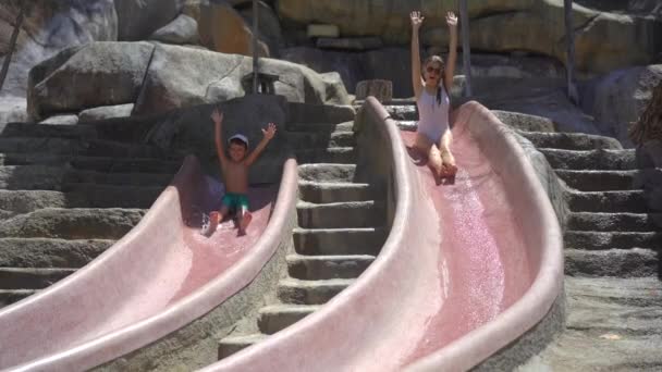 Slowmotion shot of a little boy and his mother on an aqua slides — Stock Video