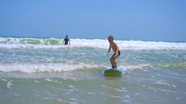 サーフインストラクターは少年にサーフィンの方法を教えています。スローモーションショット — ストック動画