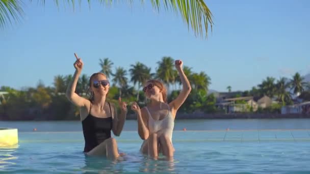 Jonge vrouwen hebben plezier in een zwembad met mineraalwater in een tropisch resort met warmwaterbronnen, watervallen en zwembaden met warm mineraalwater — Stockvideo