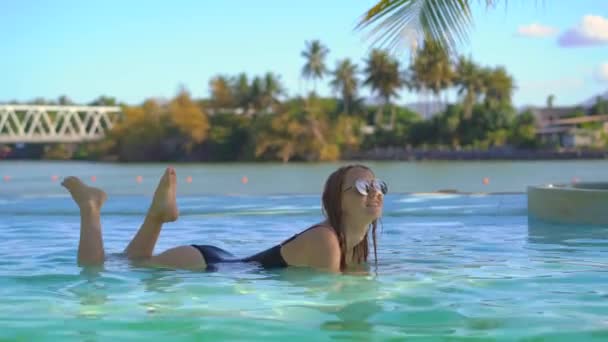 En ung kvinna kopplar av i en tropisk semesterort med varma källor, vattenfall och pooler med varmt mineralvatten — Stockvideo